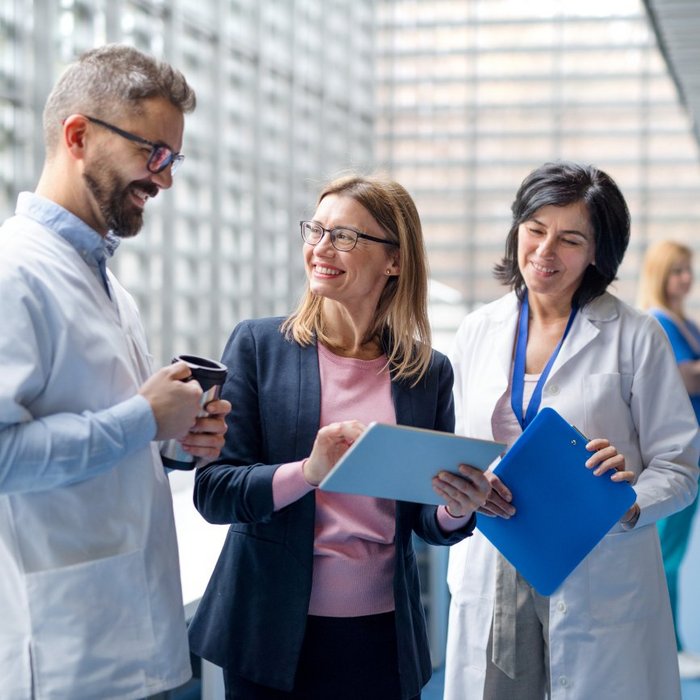 The photo shows a person having a conversation with two doctors in a clinical setting, possibly discussing health-related topics